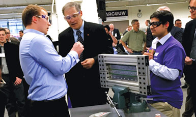 Washington Governor Jay Inslee learns about riveting from Boeing engineer Riley Hanson Smith (left) and Sai Krovvidi, a doctoral student in mechanical engineering, at the opening of the Boeing Advanced Research Center on the University of Washington campus.